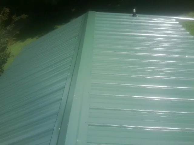 New green metal panels meeting at the ridge of a roof — Flat Roof Repair work by our crew in Mercer
