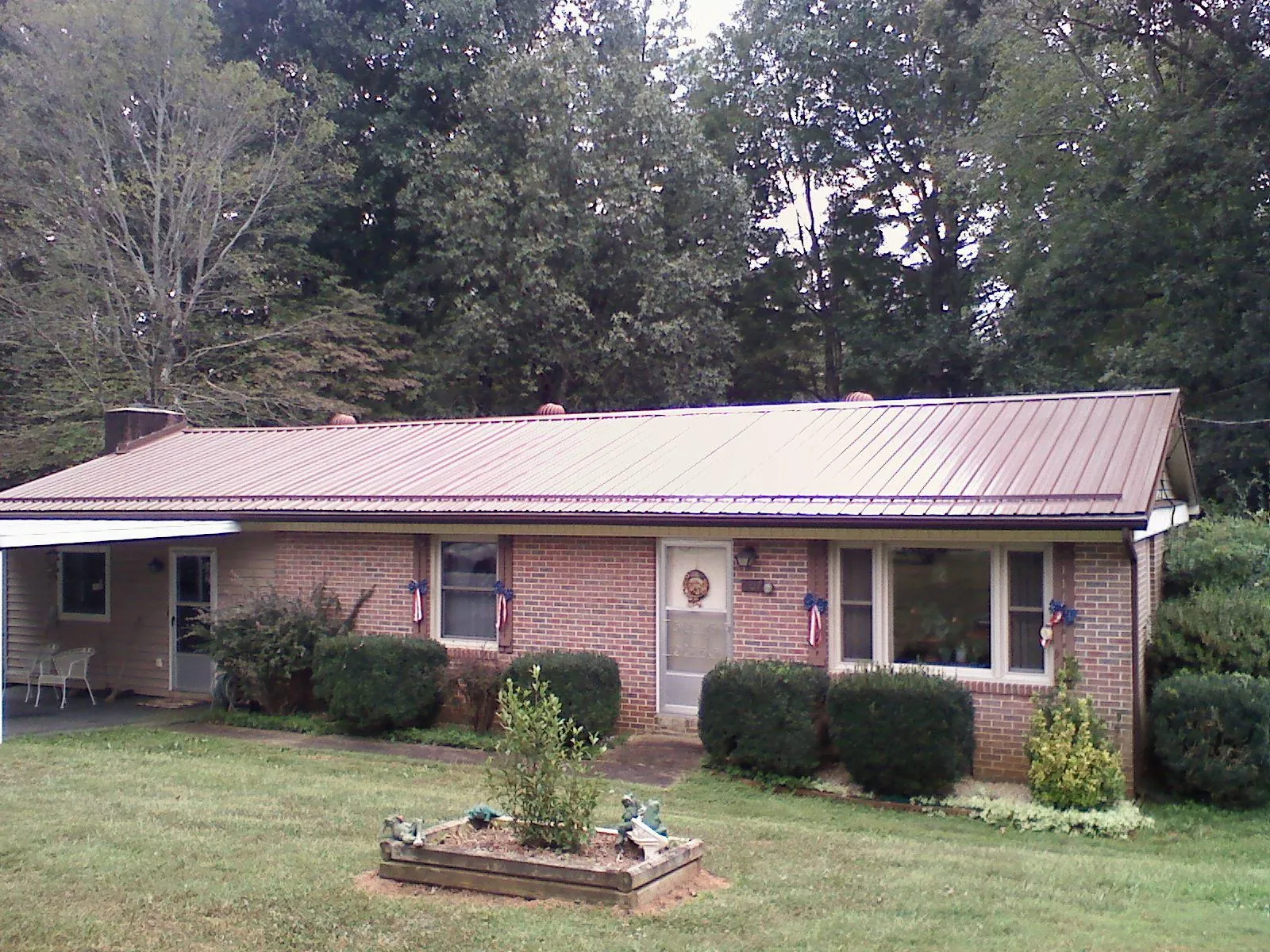 Bronze metal roof on a brick ranch home with a carport in Mercer